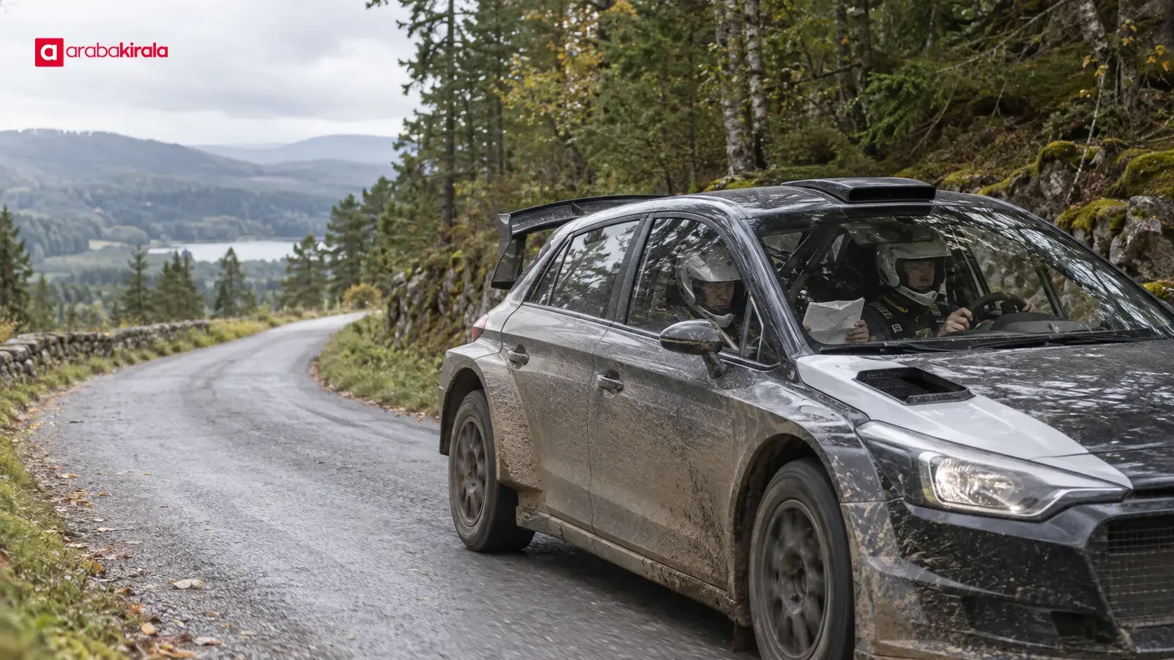 A WRC rally car travels on a connecting road between stages