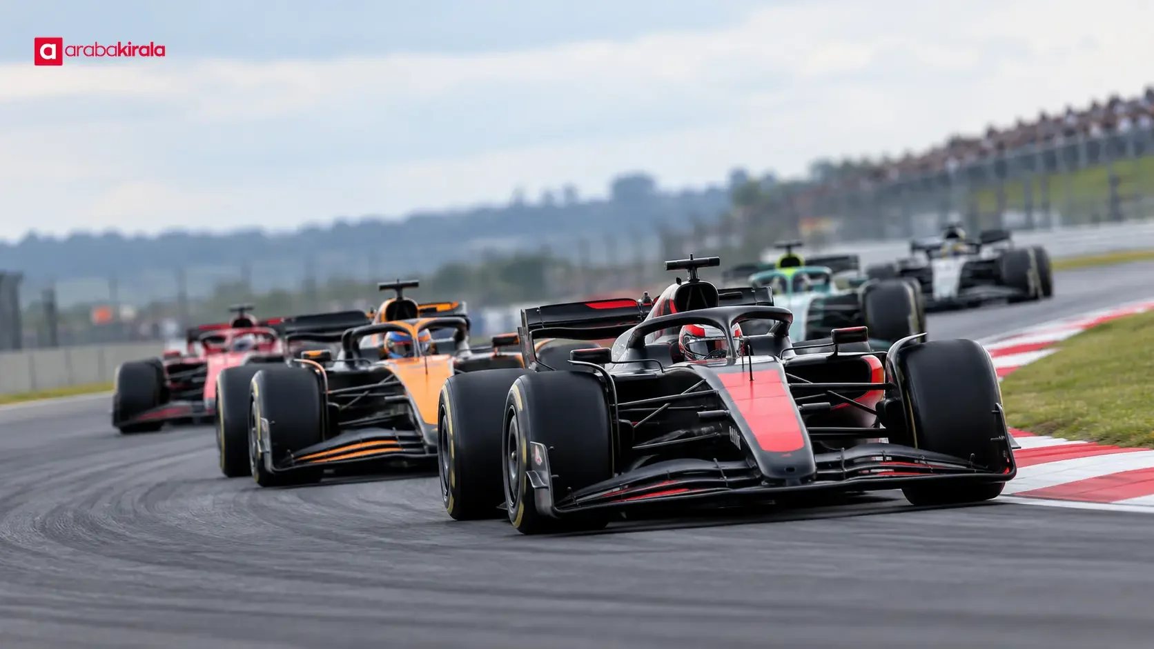 Formula 1 yarışında virajı dönen otomobiller ve tribünler